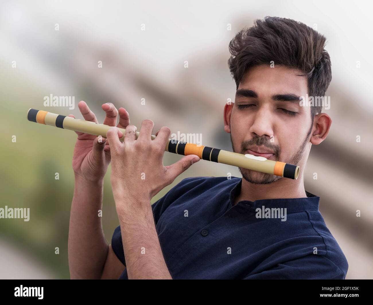 Nahaufnahme eines kleinen indischen Jungen, der seine Flöte spielt. Stockfoto