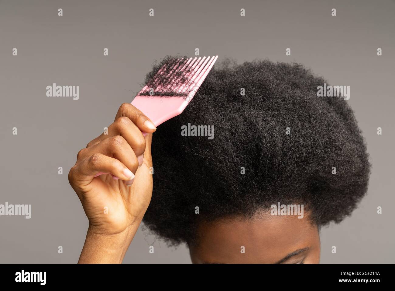 afroamerikanische Frau kämmt lockiges Haar. Ethnische weibliche Hand halten  Haarbürste an welligen Afro-Frisur Stockfotografie - Alamy