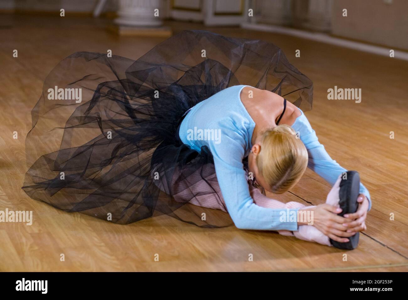 Balletttänzerin führt Dehnübungen durch, bevor sie eine Tanzprobe beginnt. Stockfoto