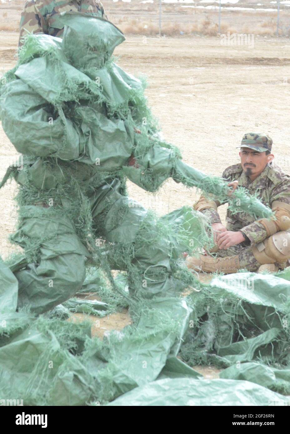 PAKTYA PROVINZ, Afghanistan – ein Grundschüler der afghanischen Nationalarmee bedeckt sich mit Sandsäcken, um ein Beispiel für die Tarnwirkung während eines Kurses im regionalen Militärausbildungszentrum von Gardez, 25. Februar 2013, zu zeigen. Der Kurs ist ein neunwöchiger Kurs, der Ende März 2013 fast 600 ANA-Soldaten absolvieren wird. (USA Armee-Foto von SPC. Tianna Waite, 115. Mobile Public Affairs Detachment) Stockfoto