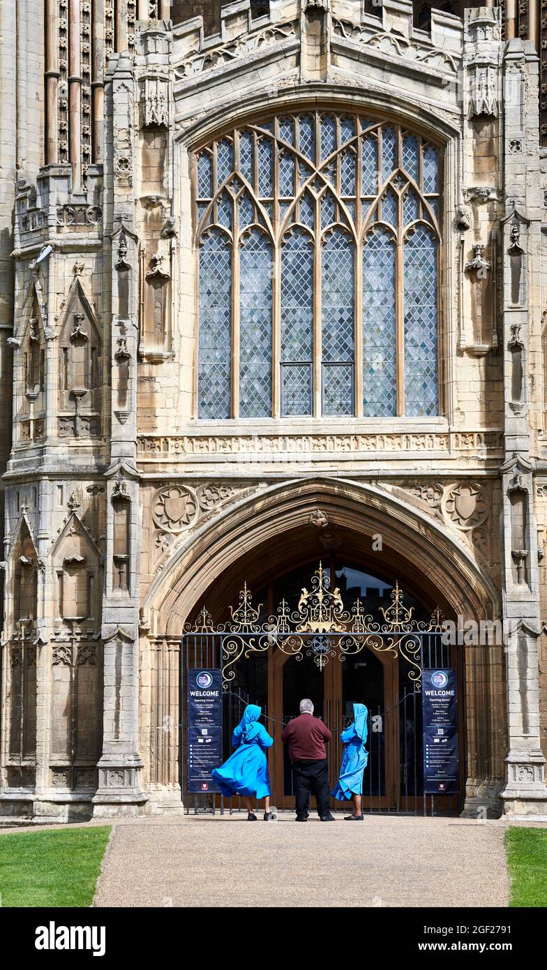 Ein englischer Priester und zwei afrikanische Nonnen am Eingang der christlichen mittelalterlichen Kirche St. Peter in Peterborough, England. Stockfoto