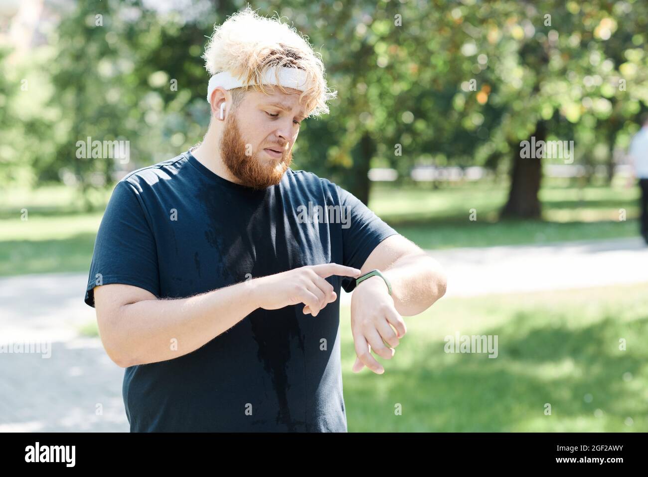 Übergewichtiger Mann mit Fitness-Tracker an der Hand beim Joggen im Park im Freien Stockfoto