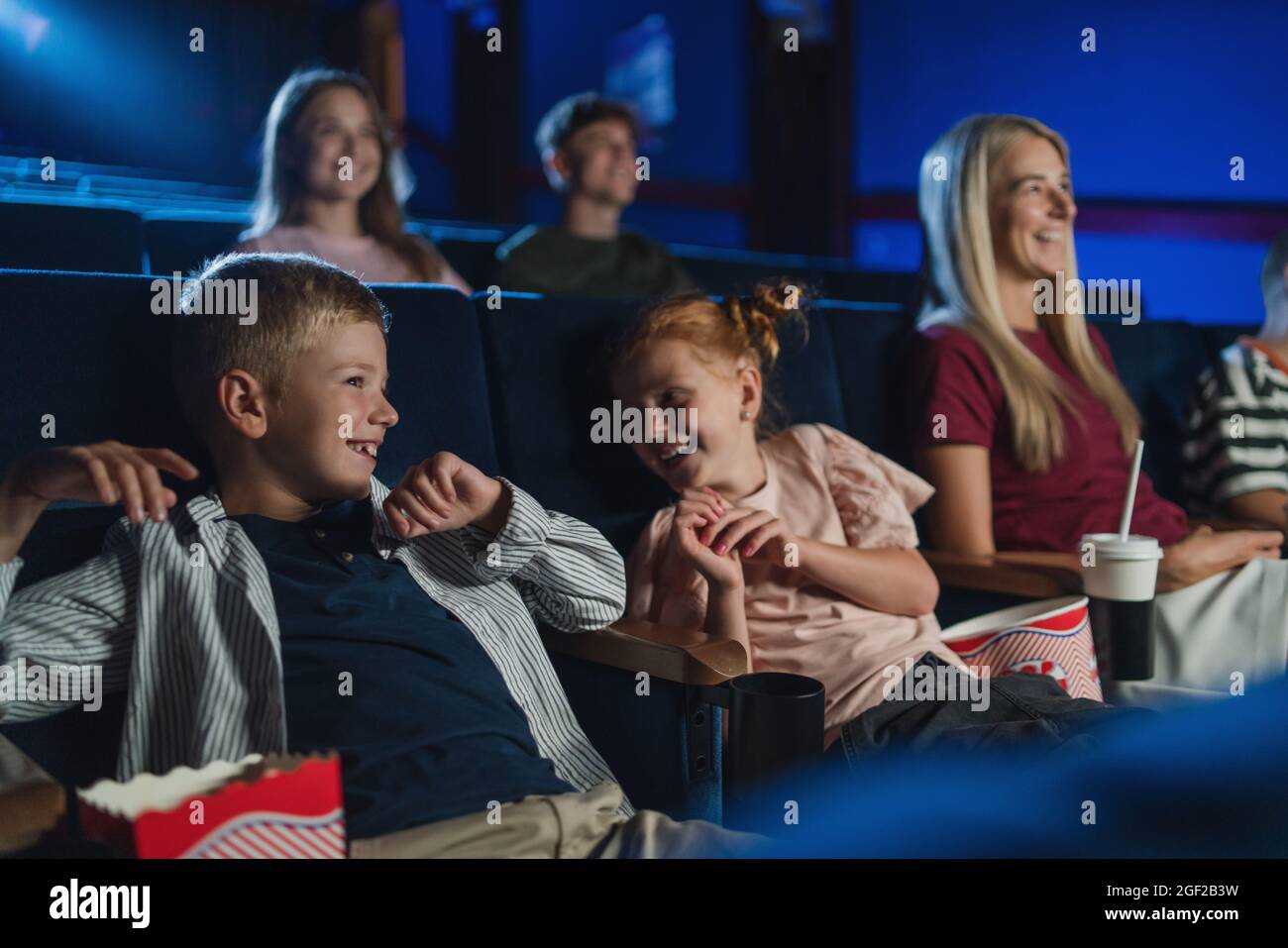 Mutter mit glücklichen kleinen Kindern im Kino, beim Film und beim Lachen. Stockfoto
