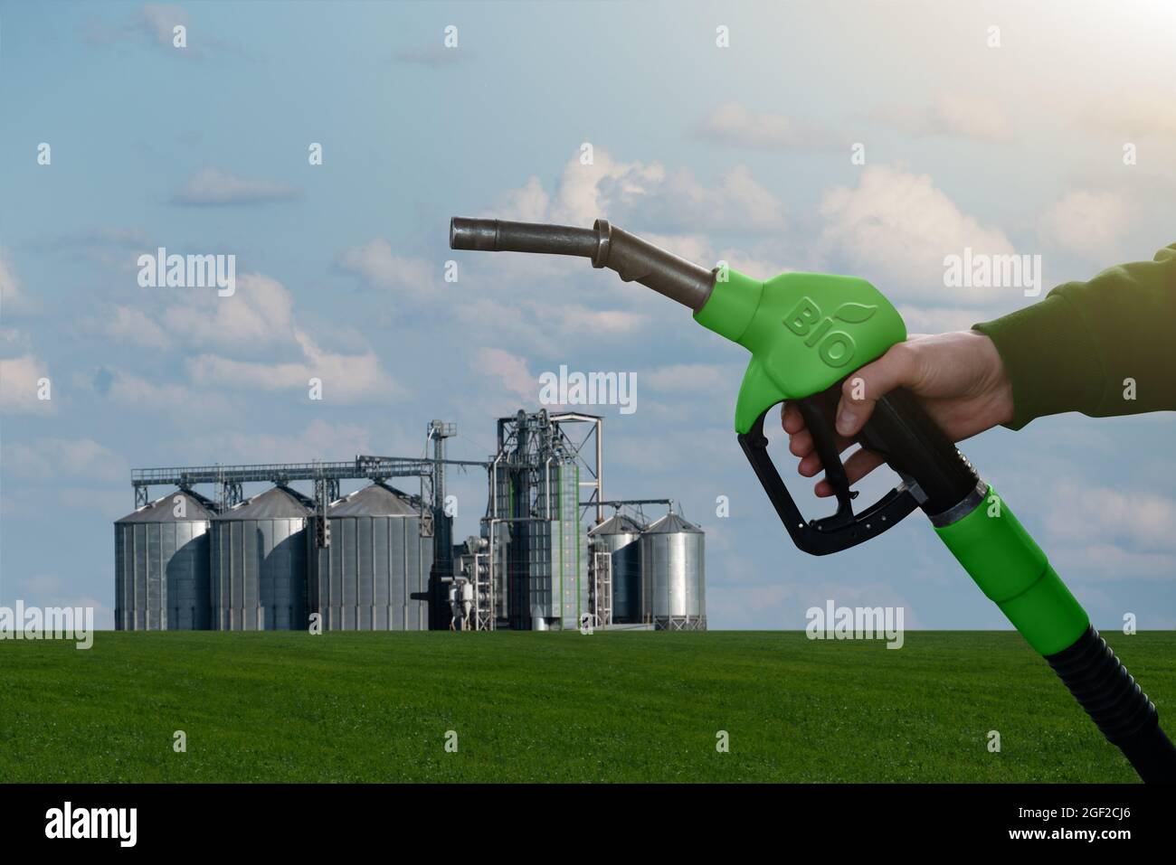 Hand mit Kraftstoffdüse mit Aufschrift Bio auf dem Hintergrund von Silos. Konzept für Biokraftstoffe Stockfoto