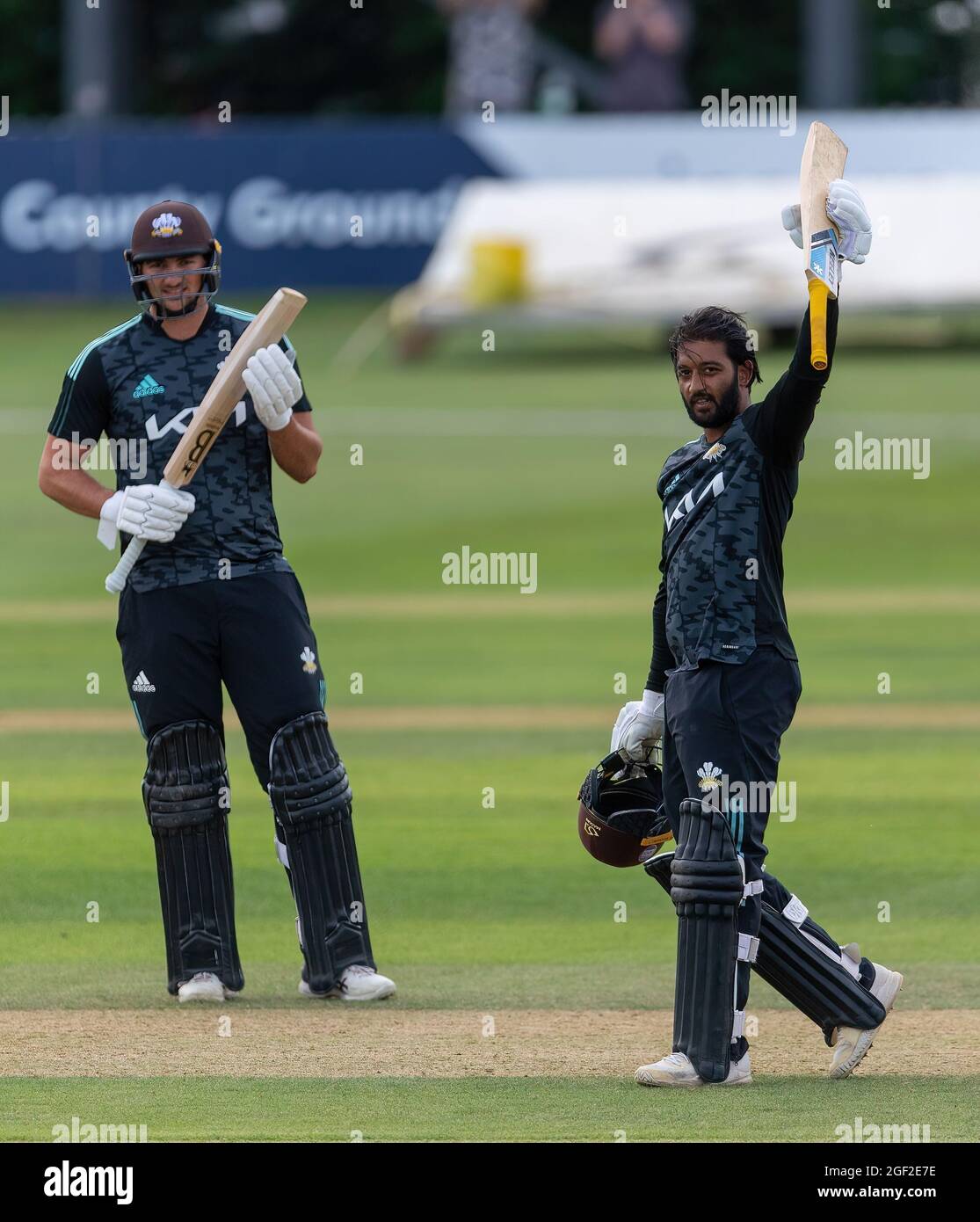 Ryan Patel von Surrey hebt seine Fledermaus, um sein Jahrhundert gegen Derbyshire in einem Royal London Cup-Spiel zu markieren. Surreys Tim David applaudiert (links). Stockfoto