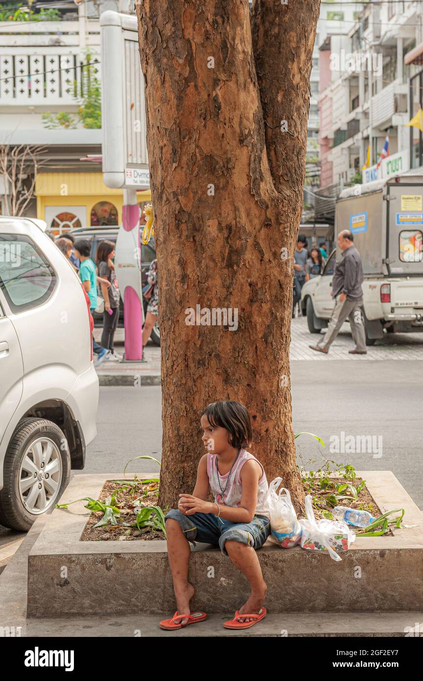 Ein thailändisches Kind, das allein in einer Straße in Bangkok in Thailand in Südostasien sitzt. Stockfoto