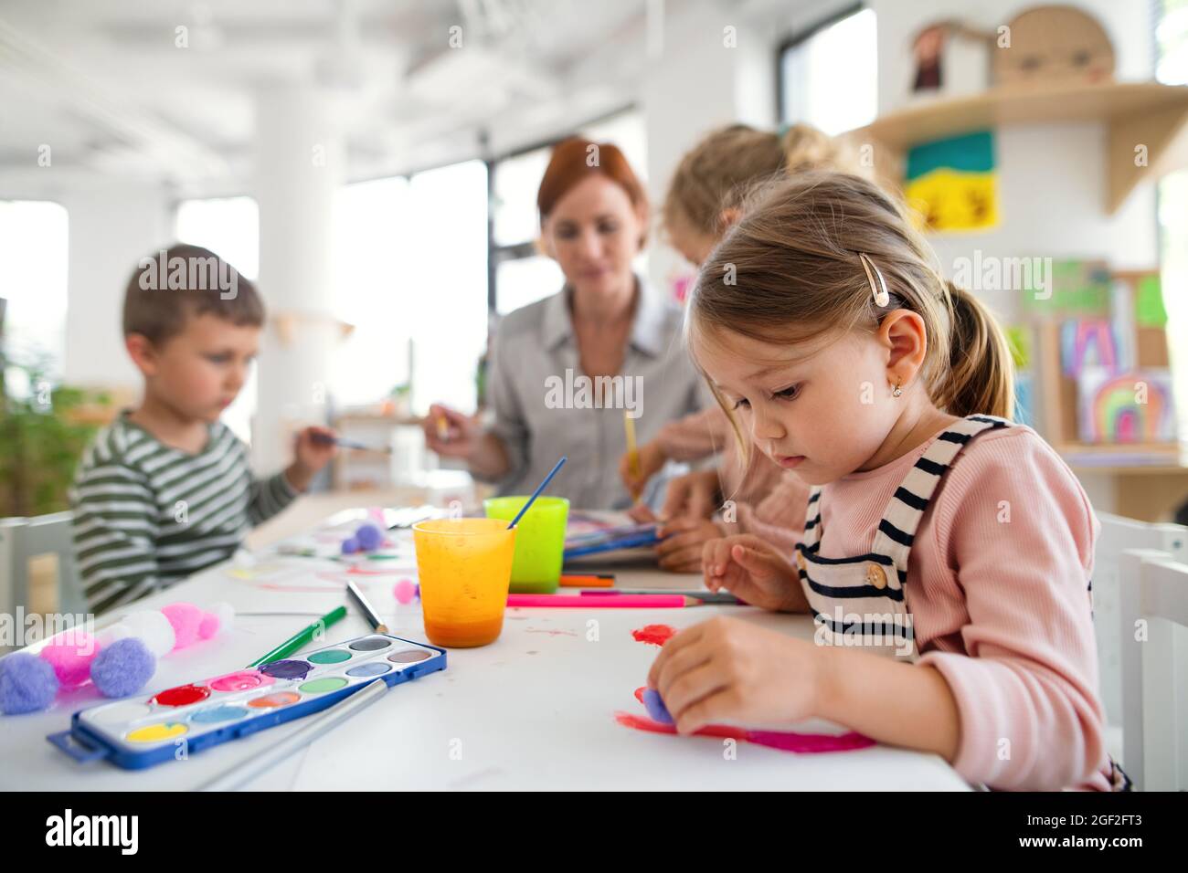Gruppe von kleinen Kindergarten-Kinder mit Lehrer drinnen im Klassenzimmer, Malerei. Stockfoto