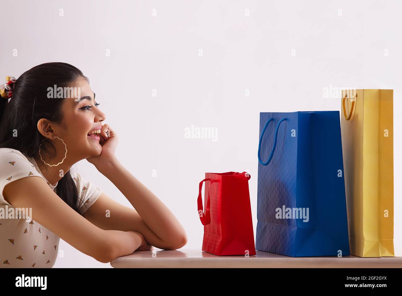Eine junge Frau, die ihre bunten Einkaufstaschen freudig ansieht. Stockfoto