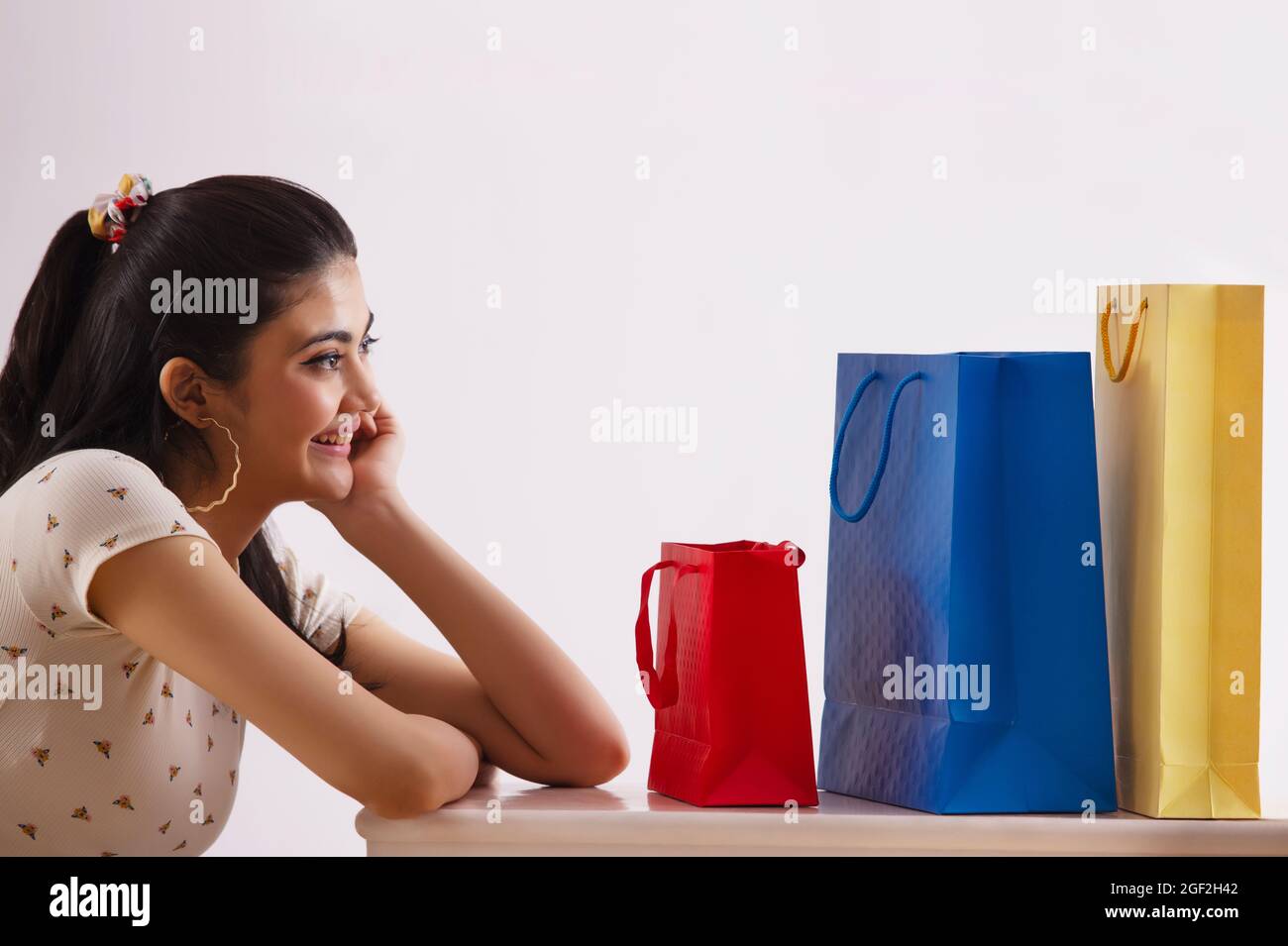 Eine junge Frau, die ihre bunten Einkaufstaschen freudig ansieht. Stockfoto