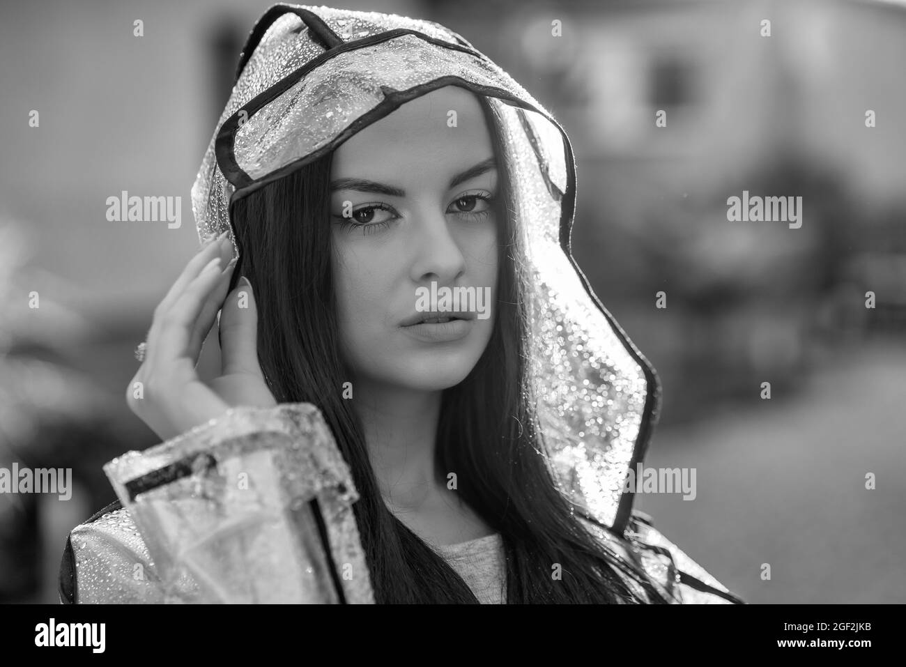 Junge schöne Frau im Regenmantel mit Kapuze an regnerischen Tagen Stockfoto