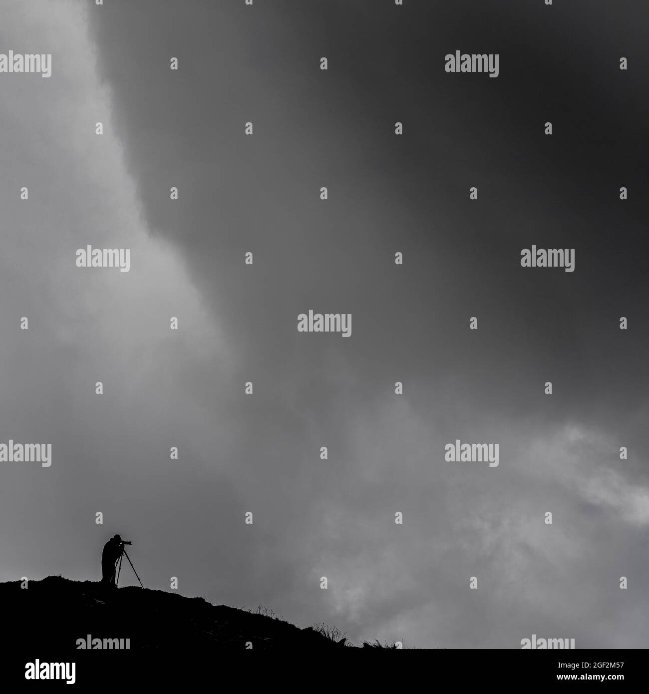 Fotograf mit Kamera auf Tripos, der gegen Sturmwolken auf Klippen in Marske-by-the-Sea, North yorkshire, großbritannien, geschilderte Stockfoto