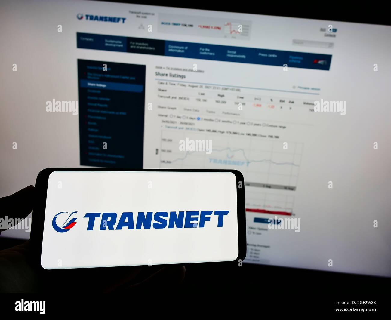 Person, die das Mobiltelefon mit dem Logo des russischen Pipeline-Unternehmens Transneft JSC auf dem Bildschirm vor der Business-Webseite hält. Konzentrieren Sie sich auf die Telefonanzeige. Stockfoto