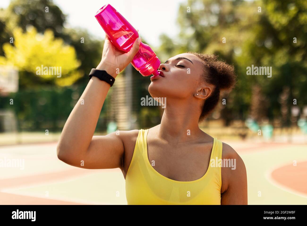 Porträt einer sportlichen schwarzen Frau in gelbem Trinkwasser Stockfoto