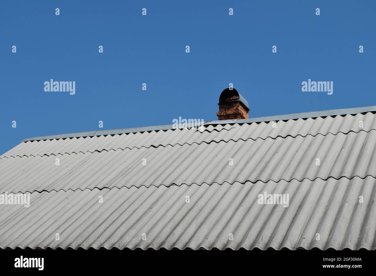 Ein Ziegelkamin für die Ofenheizung auf dem Dach eines Dorfhauses. Die Holzheizung des Landhauses. Selektiver Fokus. Stockfoto