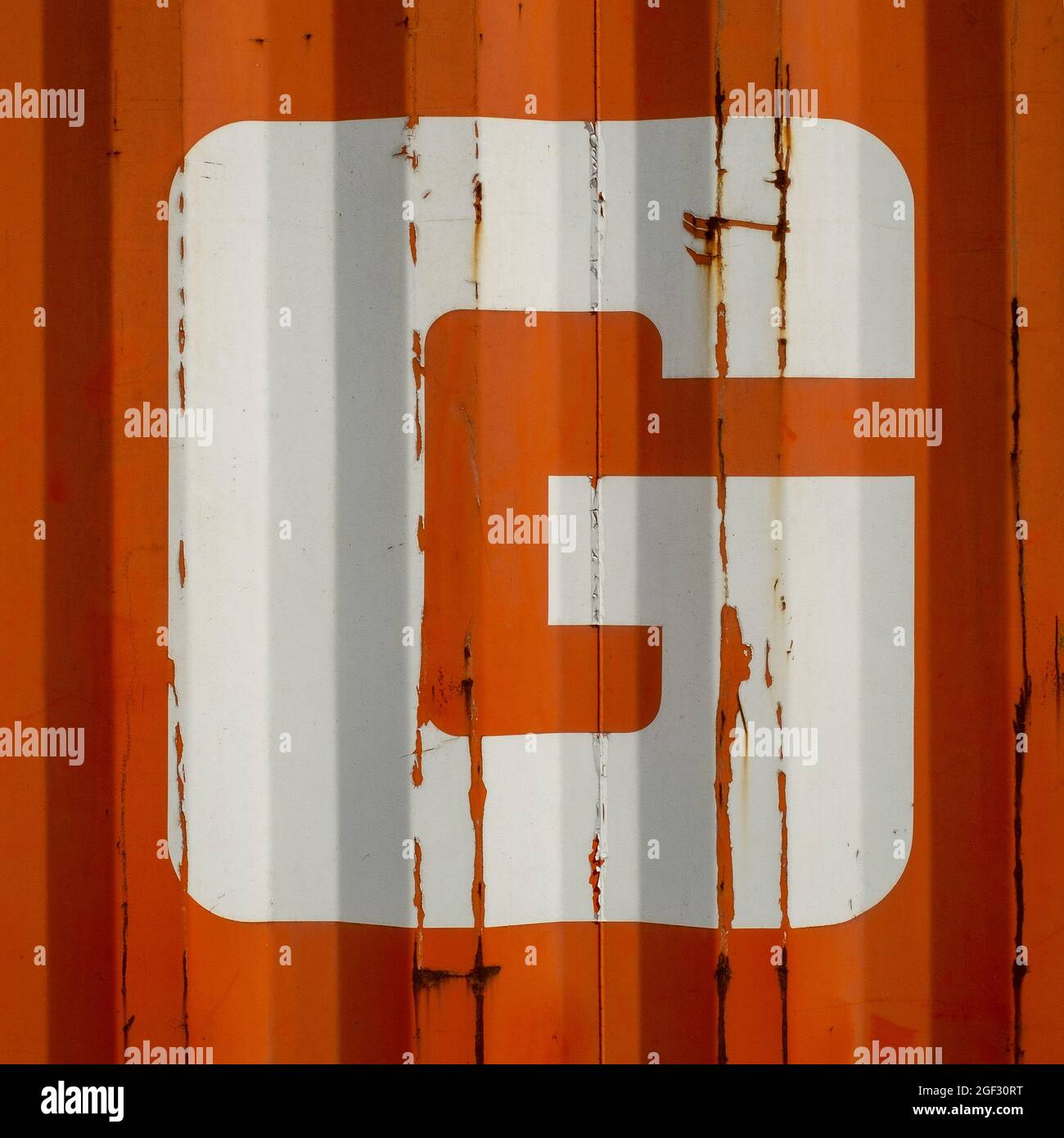 Grungen Sie einen Buchstaben G auf einem orangefarbenen gewellten emaillierten Metallhintergrund Stockfoto