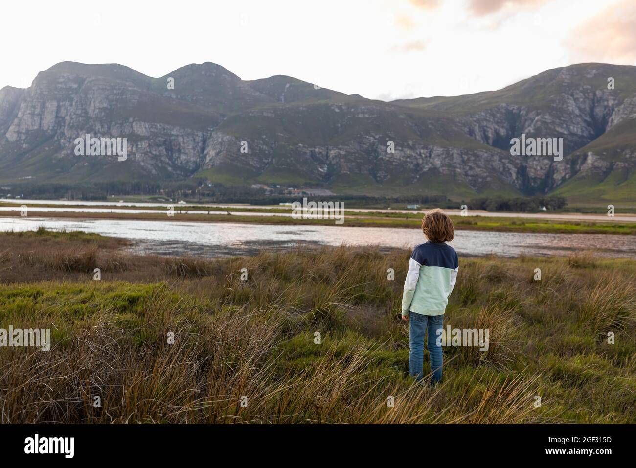 Ein Junge, der das Ufer einer Lagune im Schatten des Kleinriver-Gebirges erkundet Stockfoto