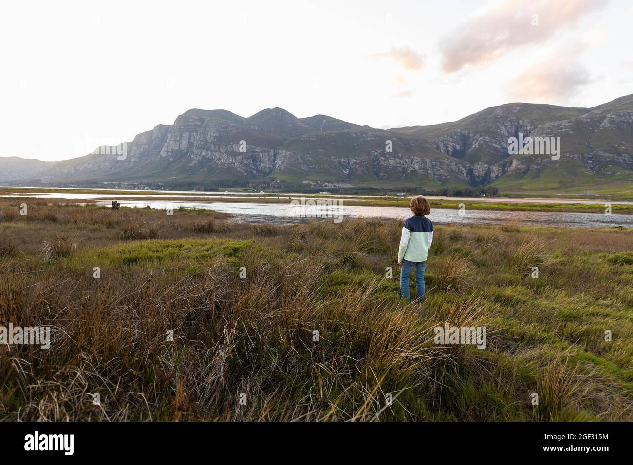 Ein Junge, der das Ufer einer Lagune im Schatten des Kleinriver-Gebirges erkundet Stockfoto