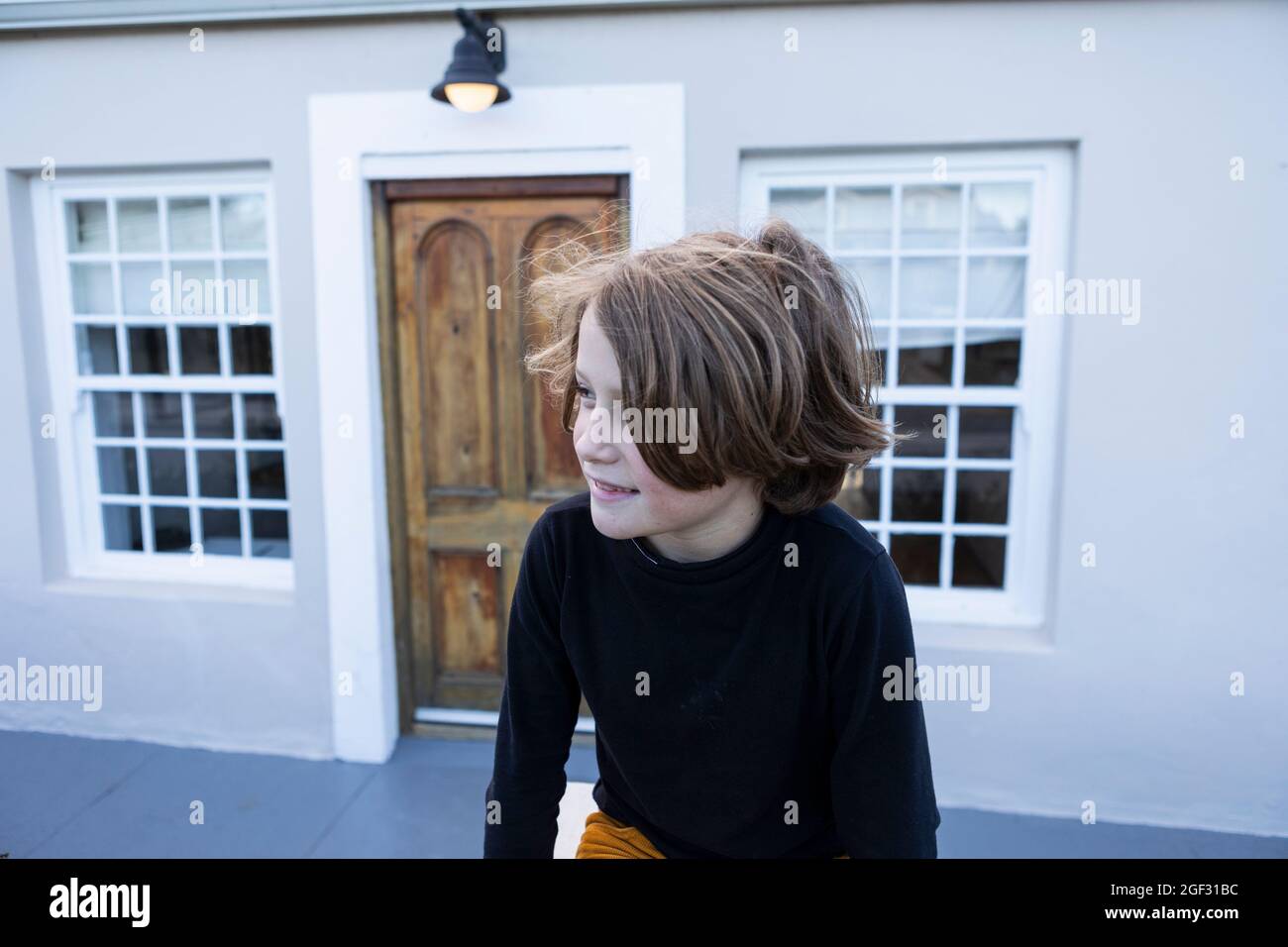 Ein achtjähriger Junge, der allein im Freien sitzt Stockfoto