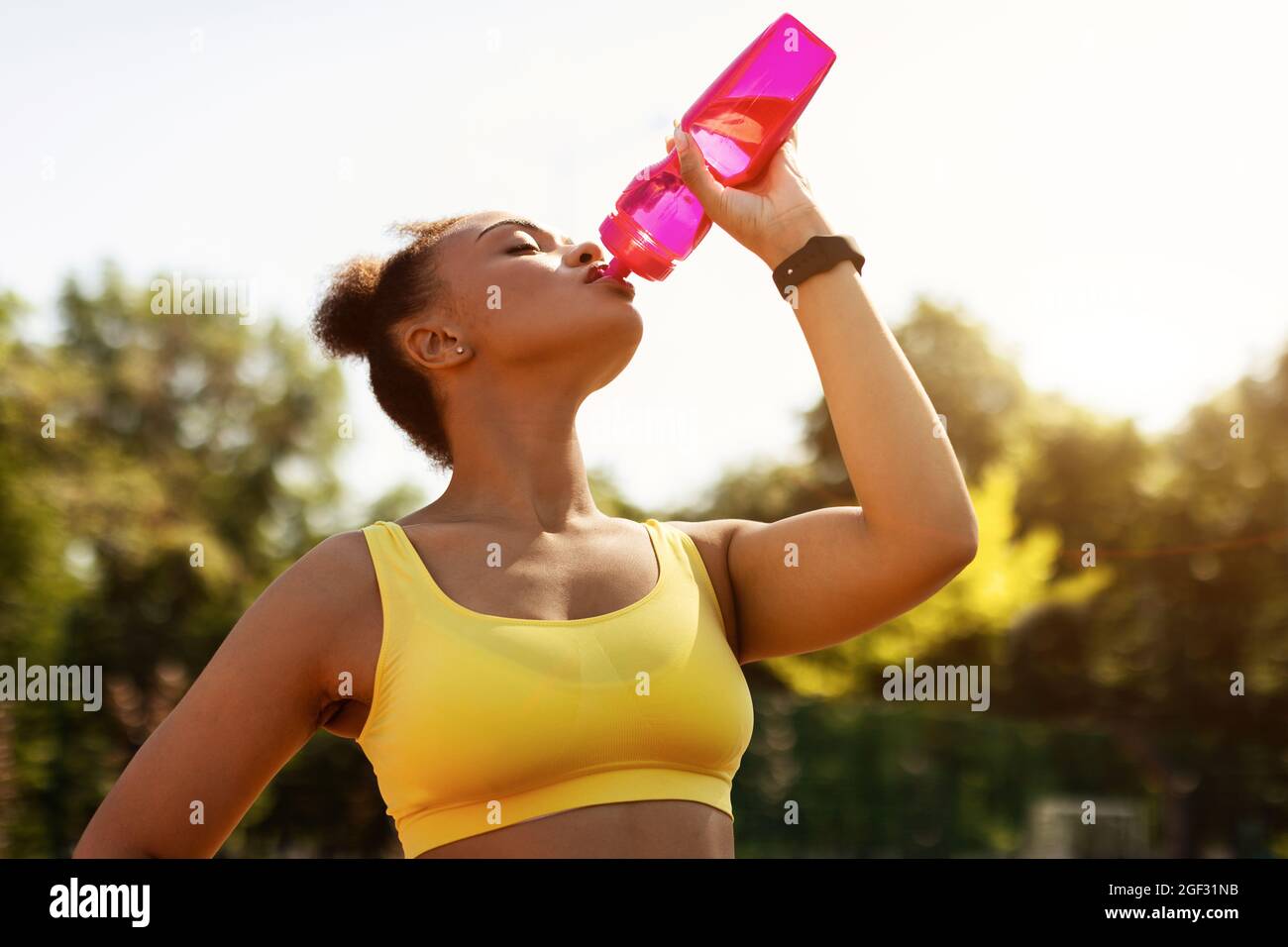 Fit schwarze Frau in gelben Sportswear Trinkwasser Stockfoto