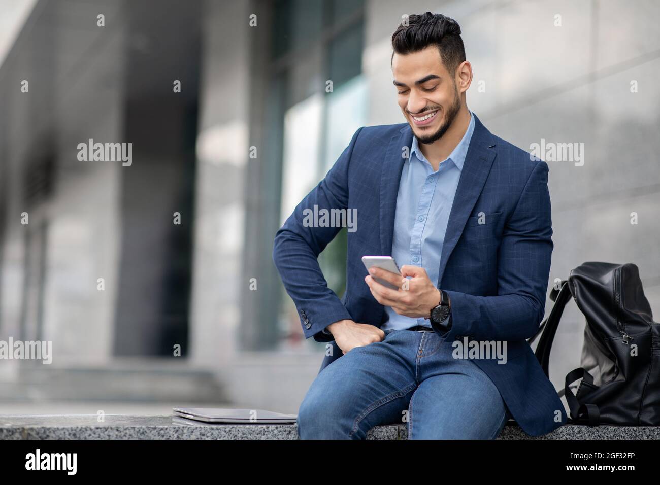 Wohlhabender Unternehmer aus dem Nahen Osten, der Mobiltelefon benutzt und sich nach einer geschäftlichen Veranstaltung ausruhte Stockfoto