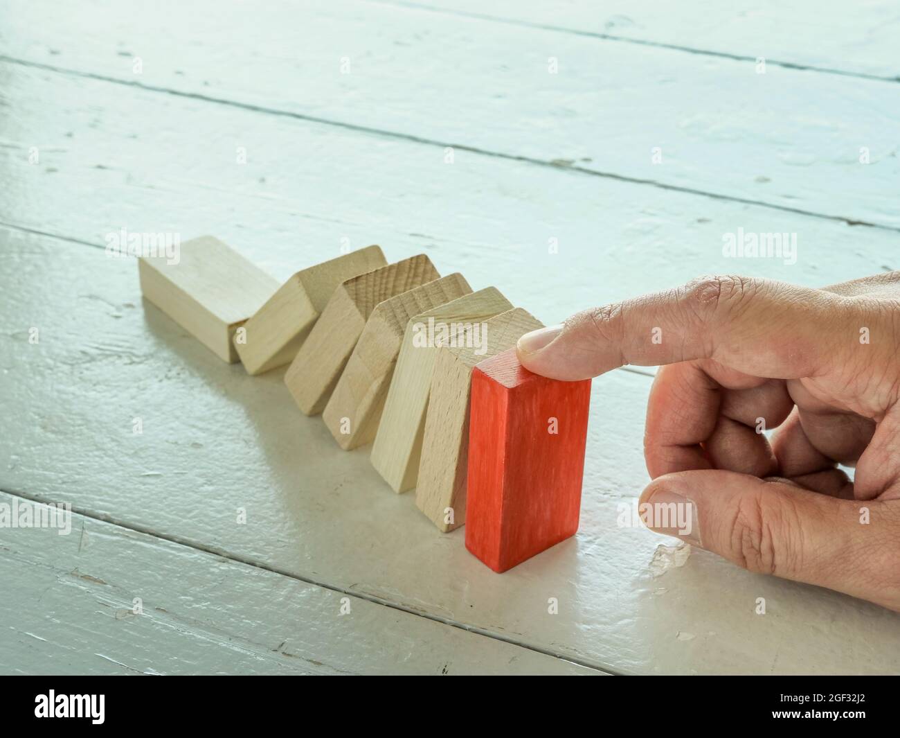Fallendes Domino-Konzept und Hand stoppt es. Krisenlösung. Stockfoto