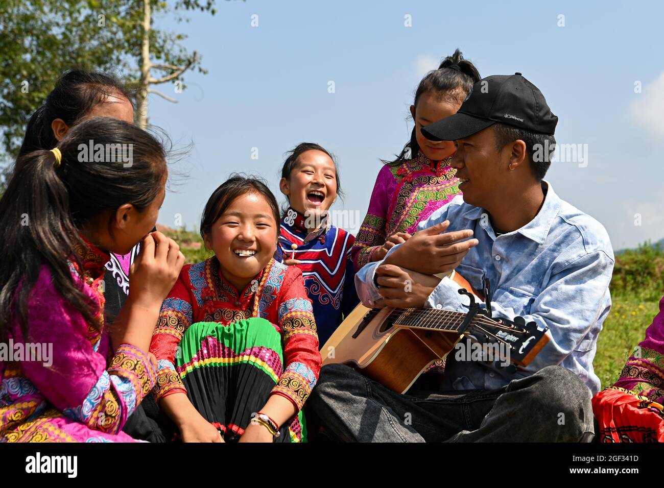 (210823) -- CHENGDU, 23. August 2021 (Xinhua) -- Mädchen und ihre Lehrerin spielen im Freien in der Stadt Dacao im Bezirk Puge, Autonome Präfektur Liangshan Yi, südwestlich der Provinz Sichuan in China, am 6. August 2021. Der Mädchenchor an der zentralen Grundschule von Dacao im Bezirk Puge erregte große Aufmerksamkeit, nachdem die Videos ihrer Performances auf kurzen Videoportalen geteilt wurden. Der Chor wurde in diesem Sommer zu einem Musikfestival in Peking, der Hauptstadt Chinas, eingeladen. (Xinhua/Tang Wenhao) Stockfoto