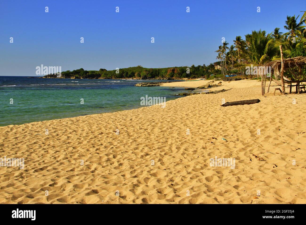 Abgeschiedener tropischer Strand mit goldenem Sand, ruhigem Wasser und ohne Menschen Stockfoto