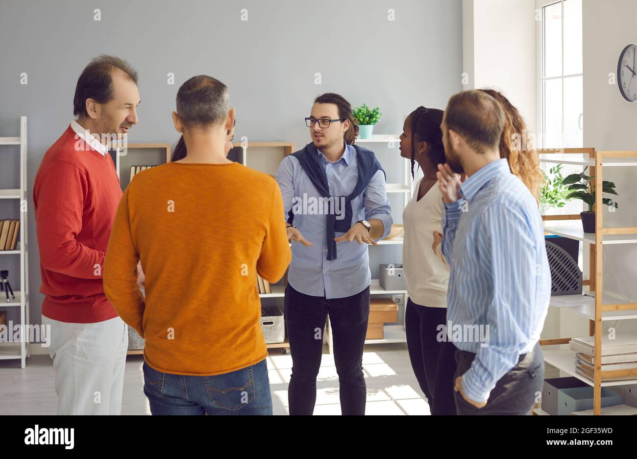 Eine Gruppe von glücklichen und vielfältigen Menschen führt informelle Gespräche in einem modernen Büro Stockfoto