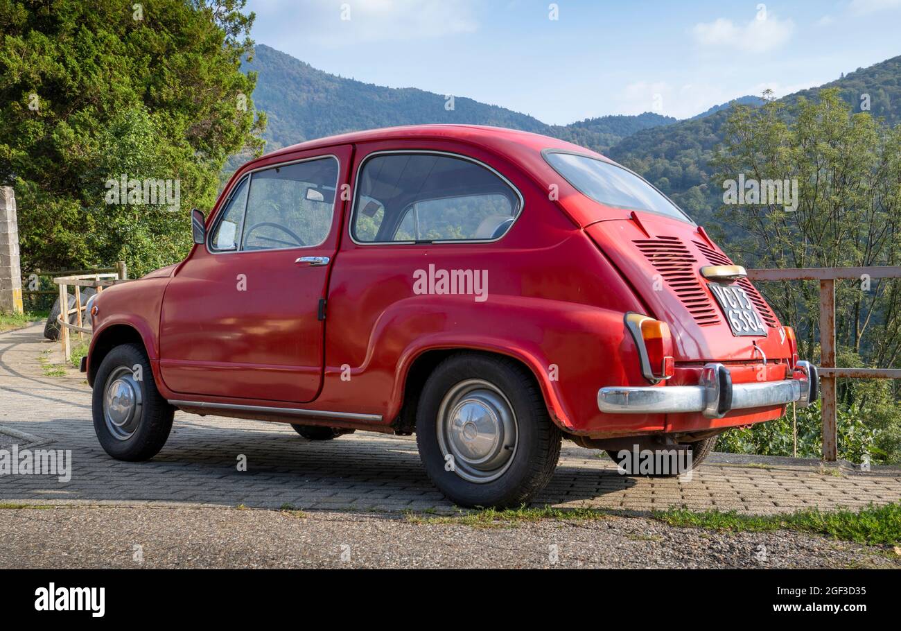 Fiat 600, kleines rotes italienisches Oldtimer, das auf einer Bergstraße geparkt ist Stockfoto
