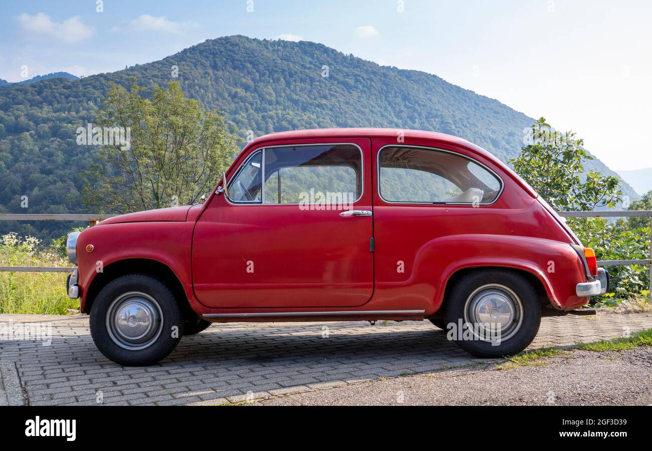 Fiat 600, kleines rotes italienisches Oldtimer, das auf einer Bergstraße geparkt ist Stockfoto