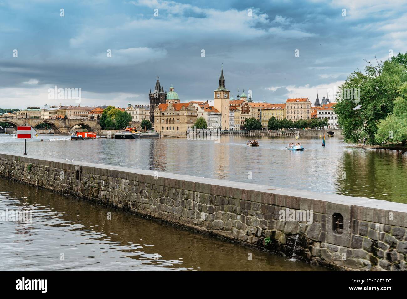 Prag, Tschechische Republik - August 4,2021. Touristen überqueren die Moldau auf Tretbooten und Spaß haben, Karlsbrücke im Hintergrund.Flussfahrt Stockfoto