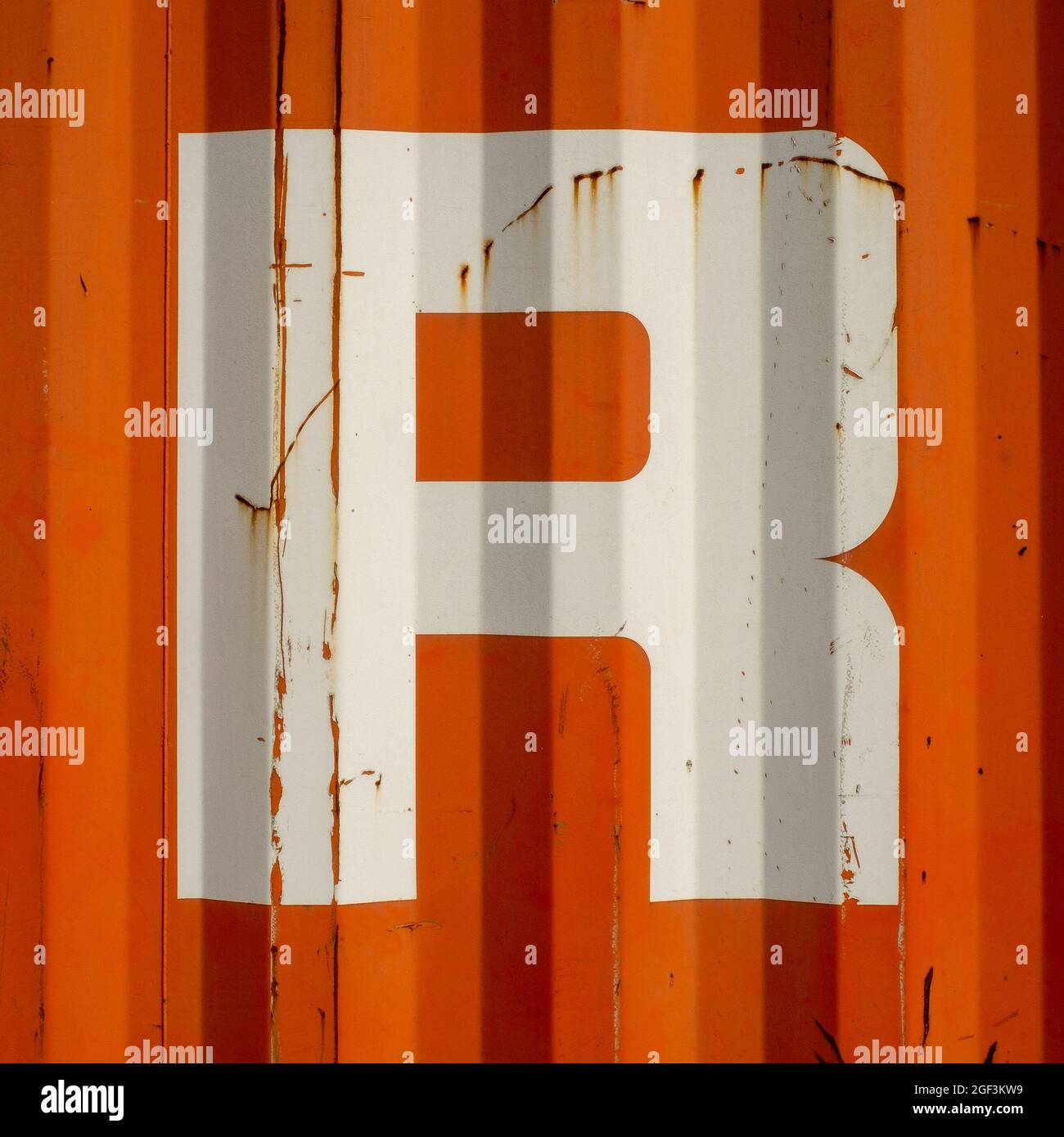 Grungen Sie einen Buchstaben R auf einem orangefarbenen gewellten emaillierten Metallhintergrund Stockfoto