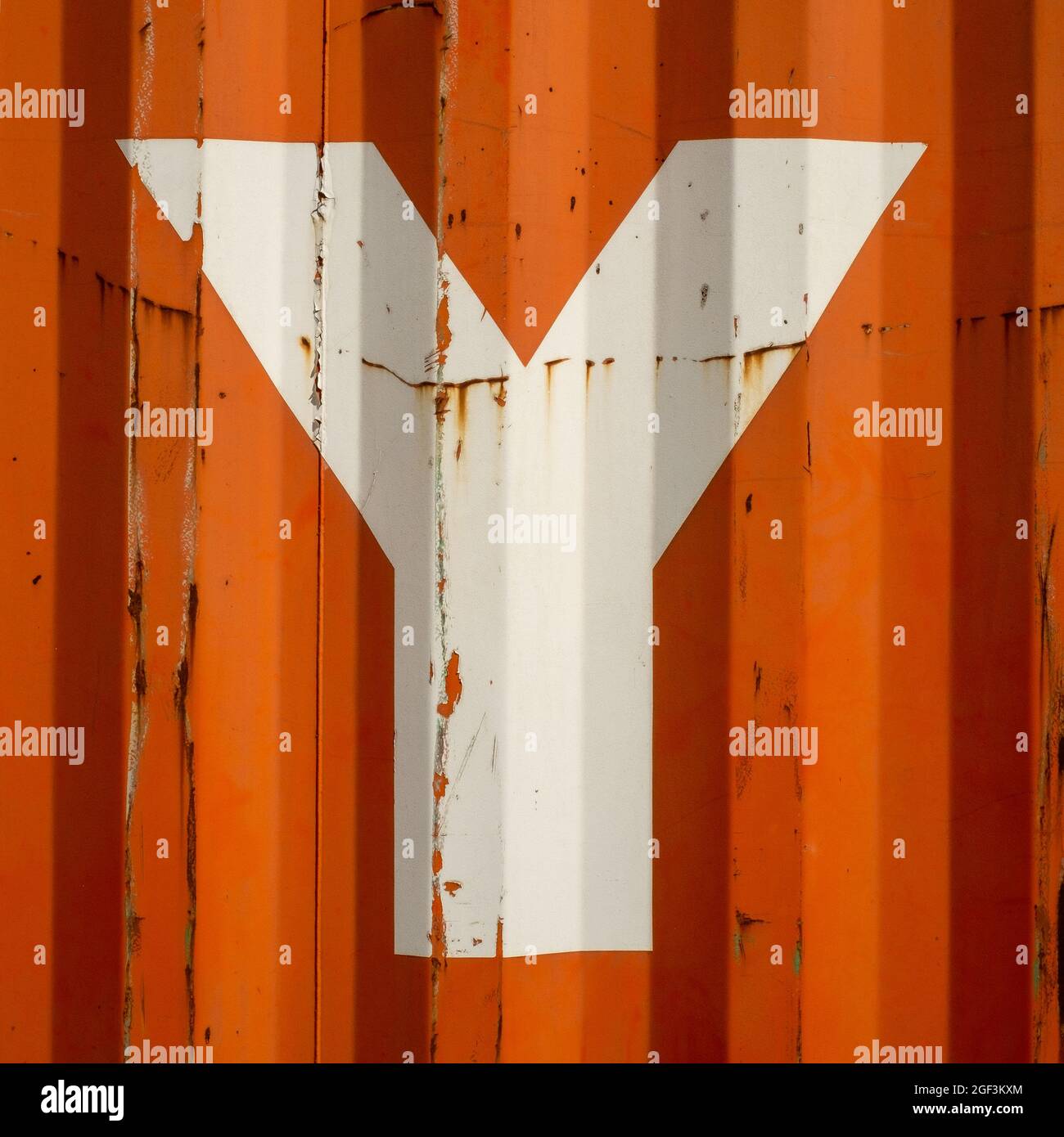 Grungen Sie einen Buchstaben Y auf einem orangefarbenen Hintergrund aus emailliertem Metall Stockfoto