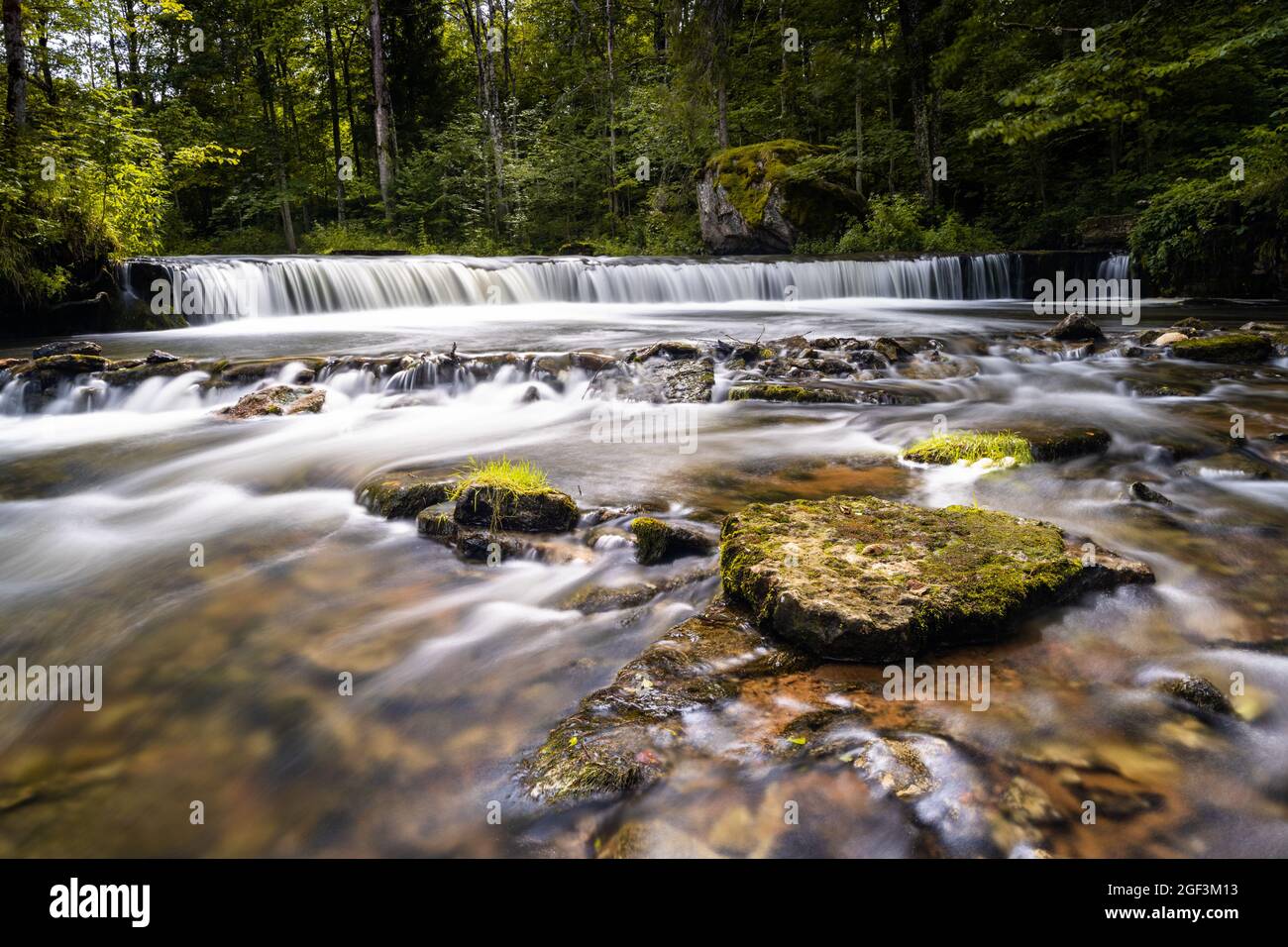 Eine idyllische Flusslandschaft im Wald mit einem kleinen Wasserfall Stockfoto