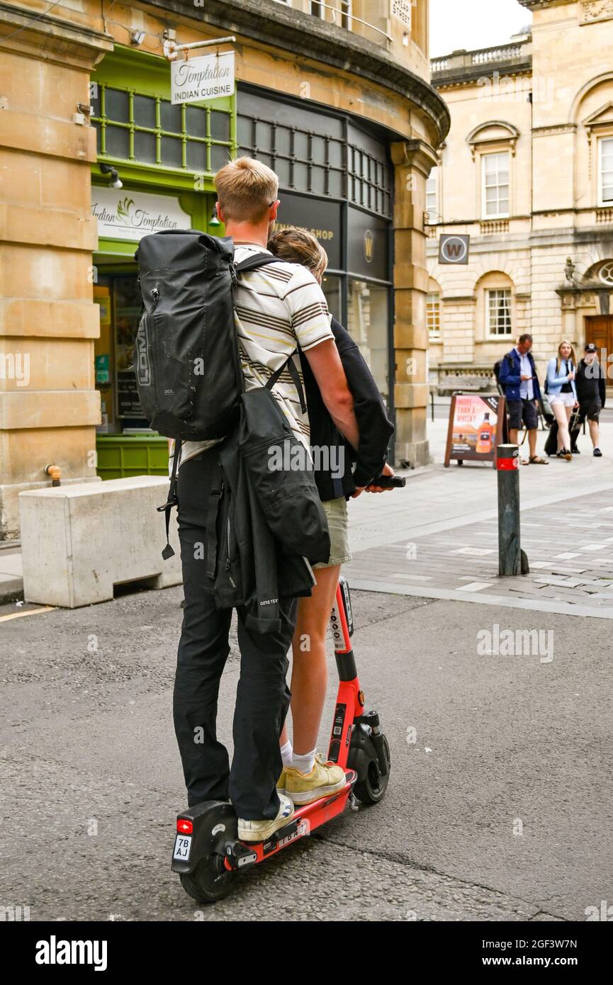 Bath, England - 2021. August: Zwei junge Menschen fahren mit einem einzigen E-Scooter durch eine Fußgängerzone im Stadtzentrum Stockfoto