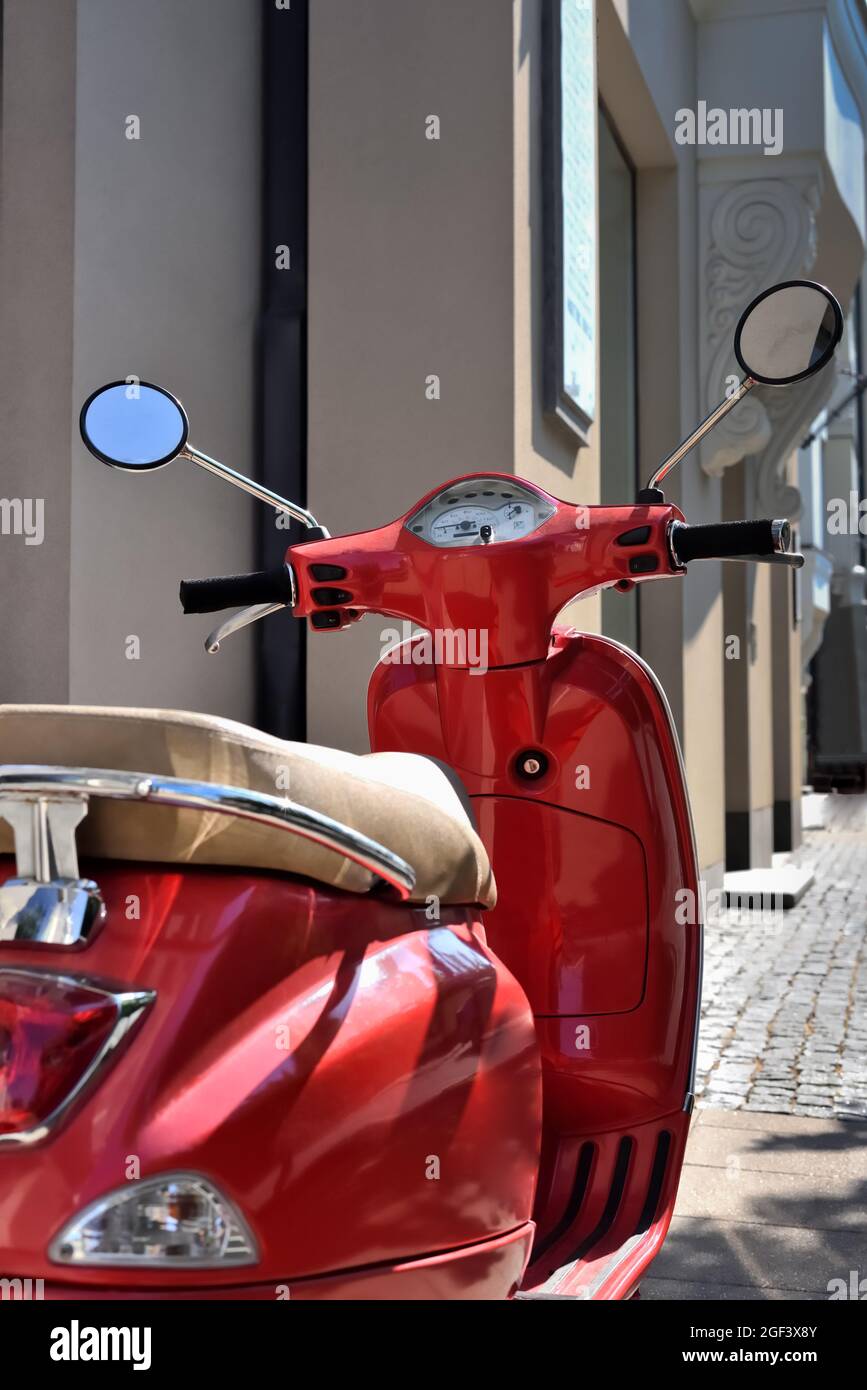 Klassischer alter roter Roller, der auf der Straße geparkt ist. Motorroller ist ein Fahrzeug und Transport in der Stadt. Stockfoto