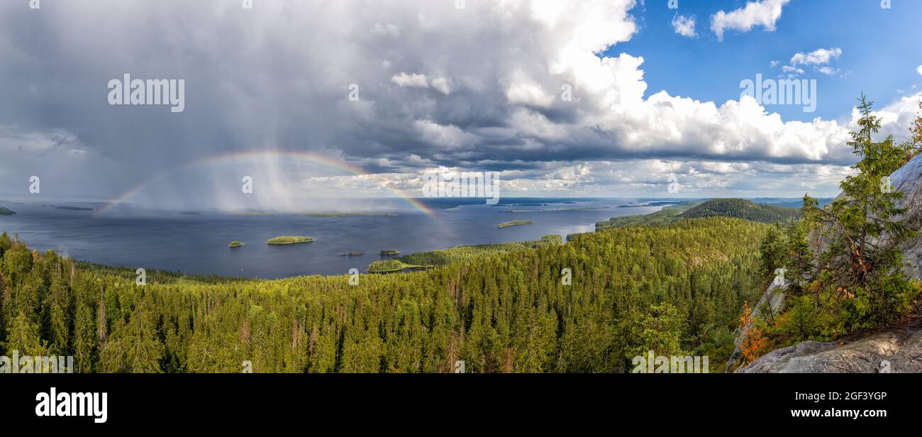 Ein Panoramablick auf den Pielina-See und die Inseln im Koli-Nationalpark in Finnland mit einem Regenbogen unter einem ausdrucksstarken bewölkten Himmel Stockfoto
