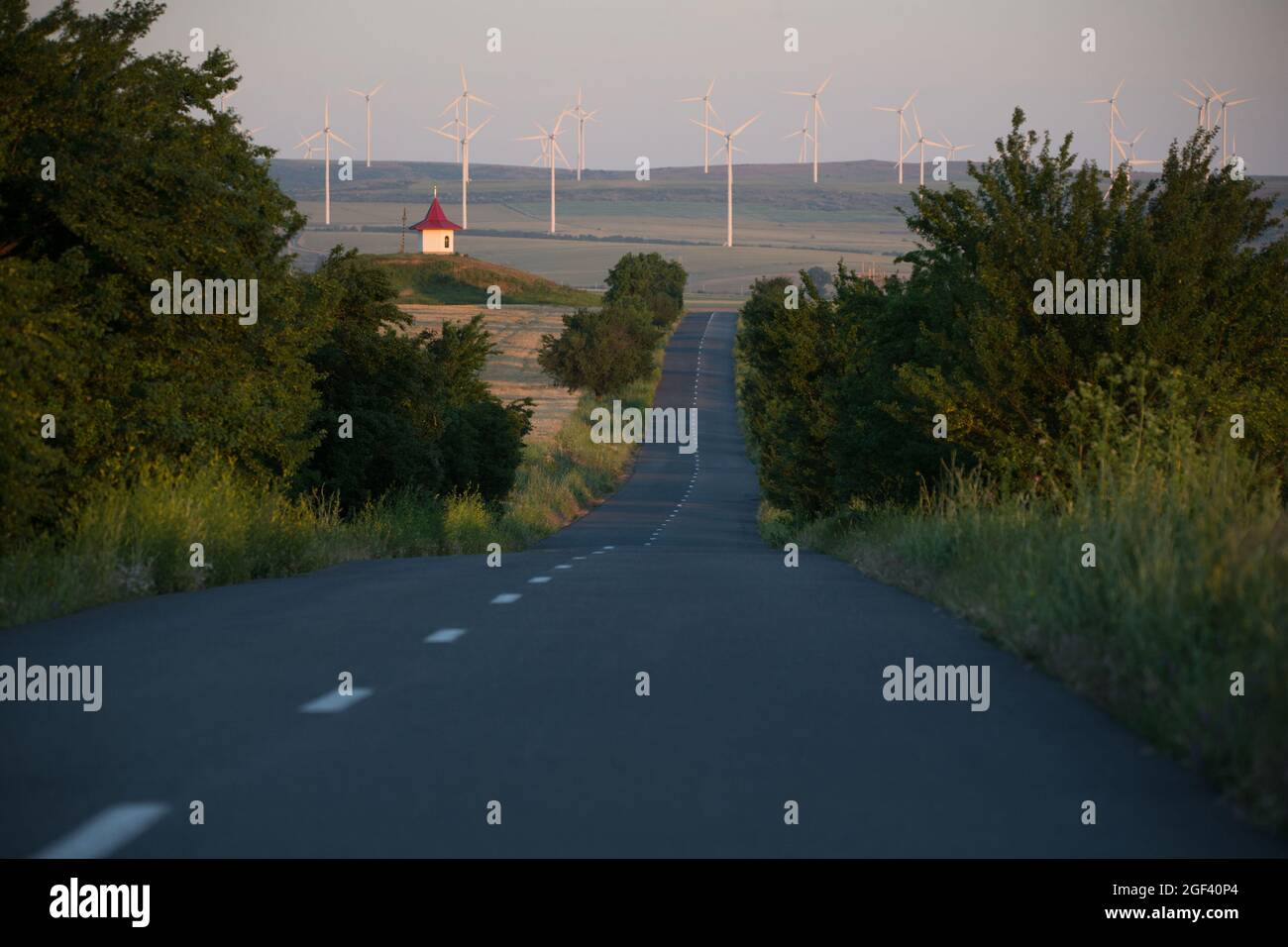 Rumänische Straße mit Windturbinen bei Sonnenuntergang Stockfoto