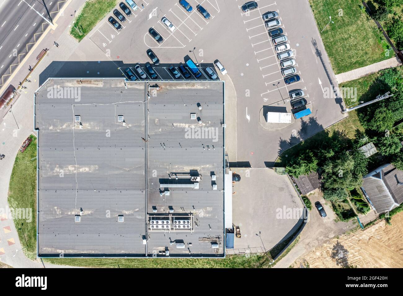 Schindeldach des Einkaufszentrums mit Lüftungssystemen. Reihen von Autos auf dem Parkplatz in der Nähe von Supermarkt. Luftaufnahme von oben Stockfoto