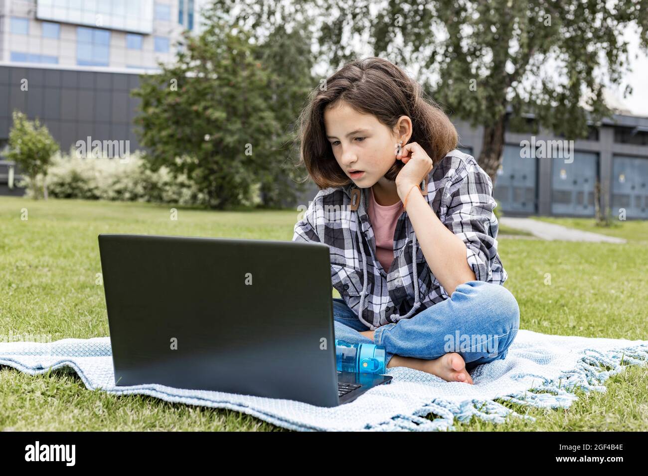 Ein Schulmädchen schaut sich einen Internetkurs an und studiert aus der Ferne. Das Mädchen nutzt drahtlose Internet-Technologien. Ein hübsches junges Mädchen im Teenageralter sitzt auf dem Stockfoto