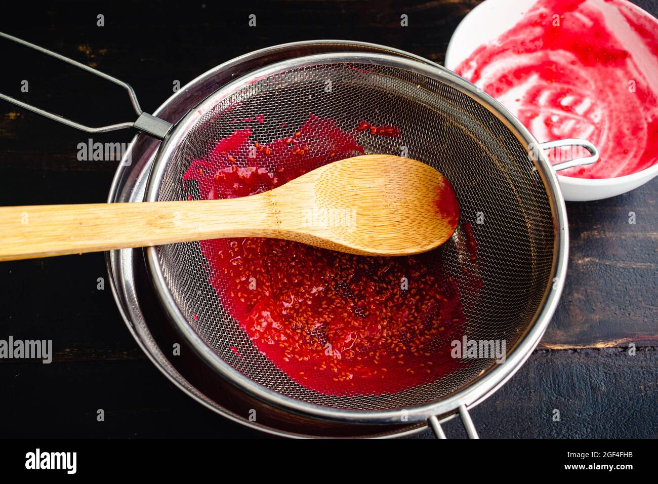Raspberry-Püree durch ein Mesh-Sieb straining: Samen aus frischem Himbeer-Püree mit einem Mesh-Sieb straining Stockfoto