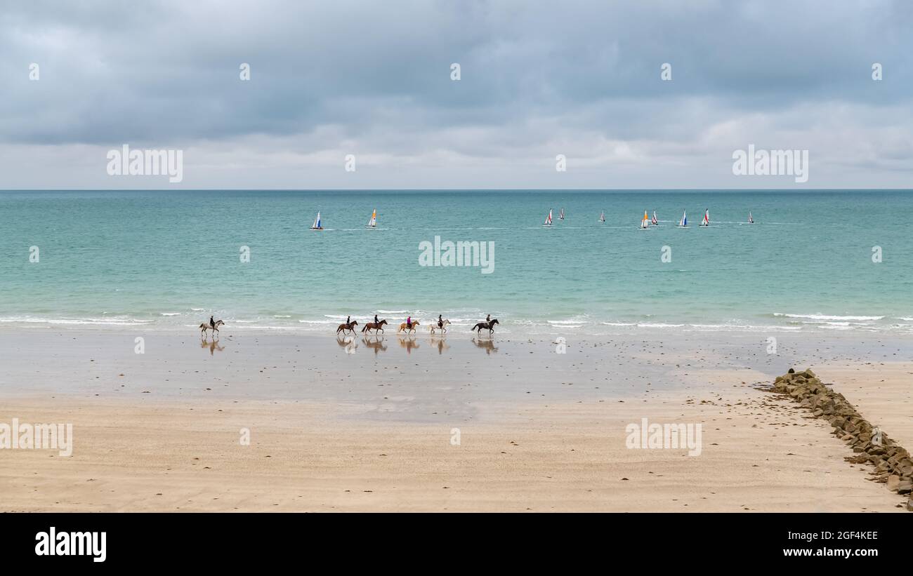 Schöner Strand in Agon-Coutainville in der Normandie, mit Segelfahrern und Reitern Stockfoto