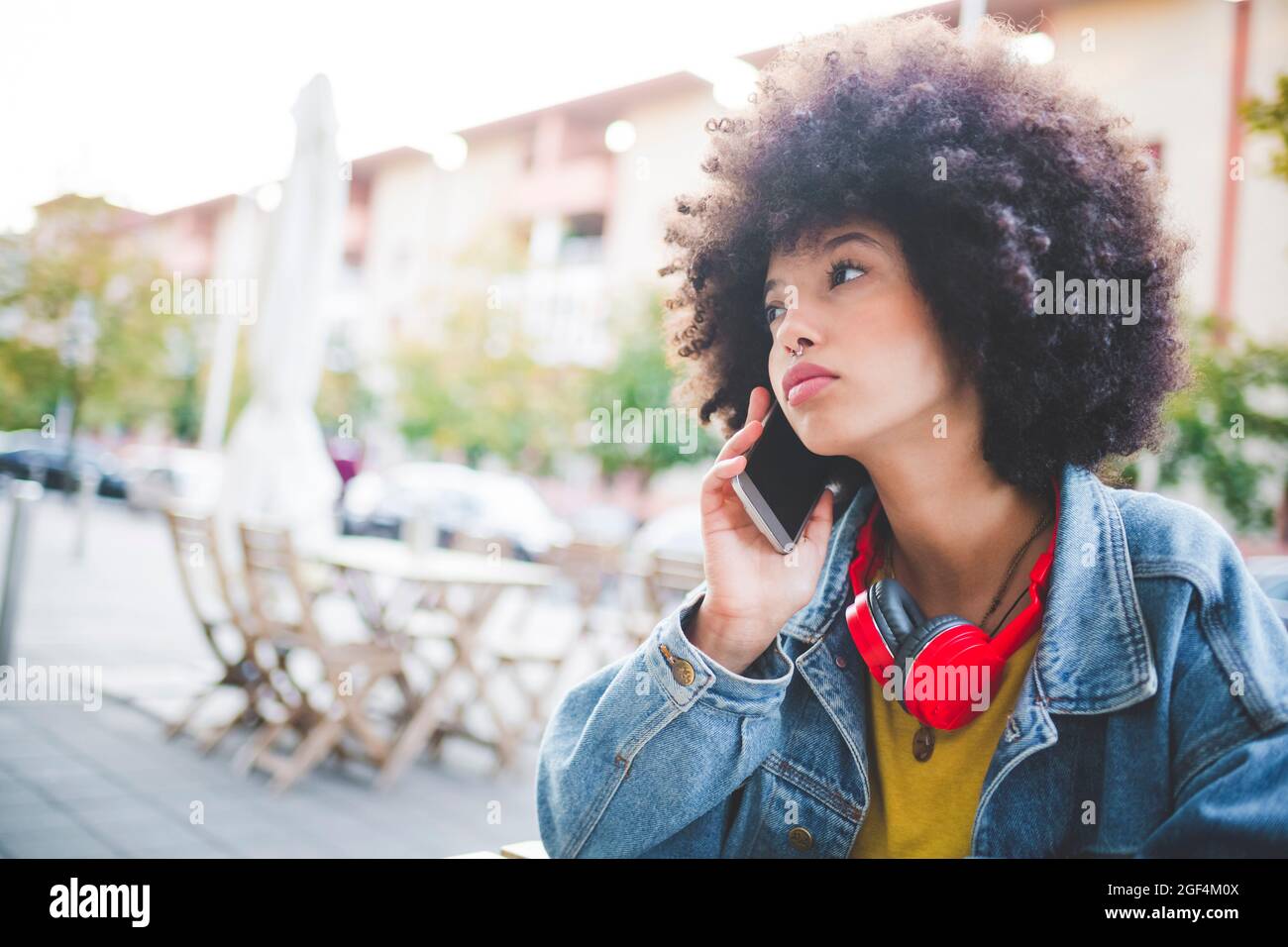 Junge Frau mit Afro-Frisur am Telefon in der Stadt Stockfoto