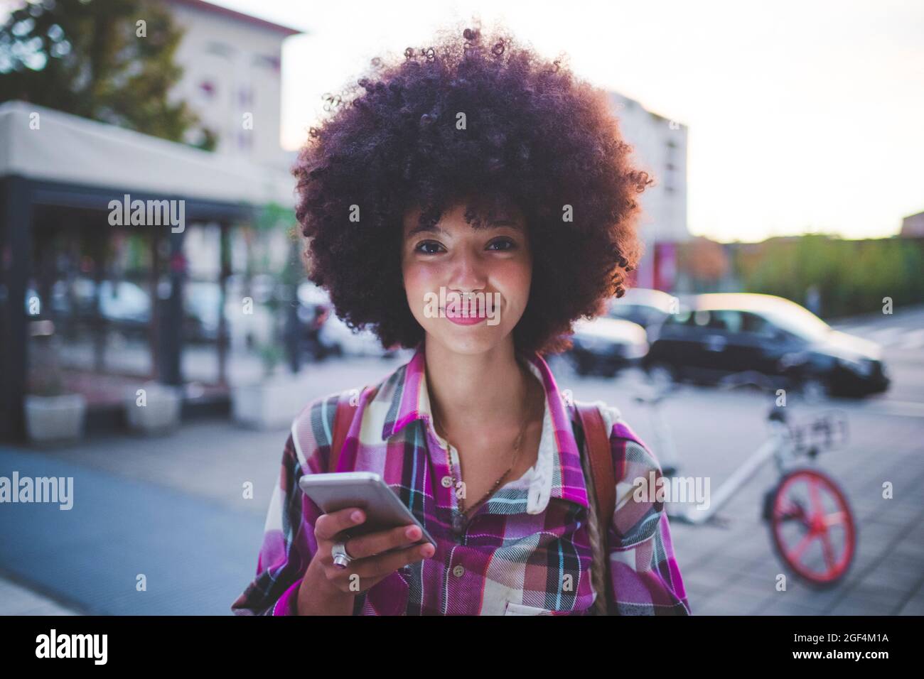 Porträt einer selbstbewussten jungen Frau mit afro Frisur in der Stadt in der Dämmerung Stockfoto