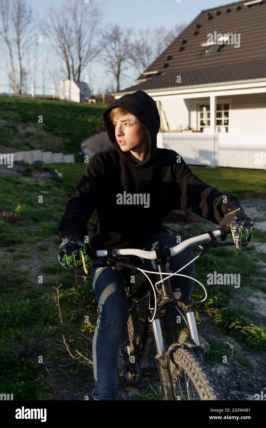 Junge mit Fahrrad, der in den Hinterhof schaut Stockfoto