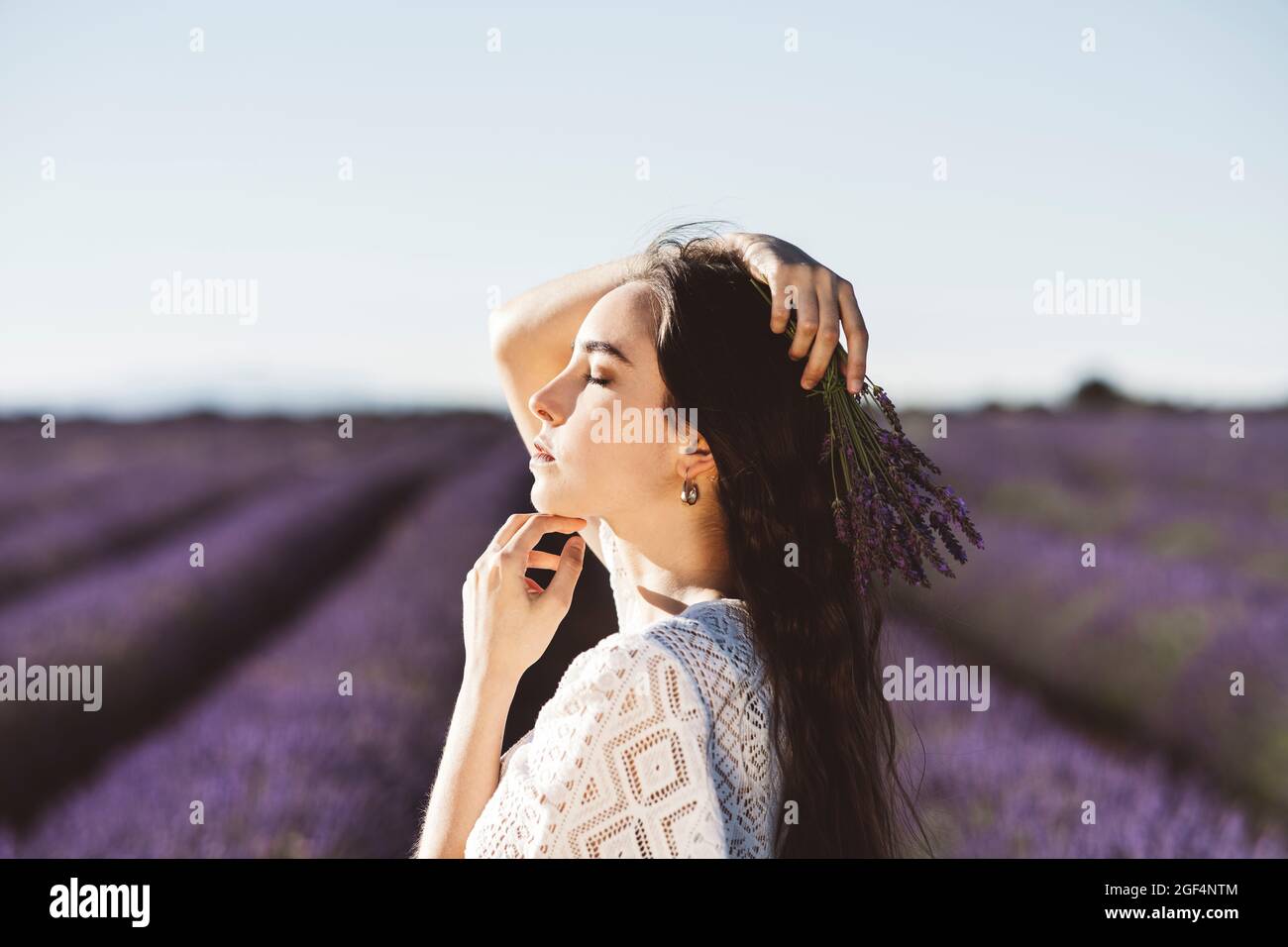 Junge Frau mit geschlossenen Augen in Lavendelfeld während sonnigen Tag Stockfoto