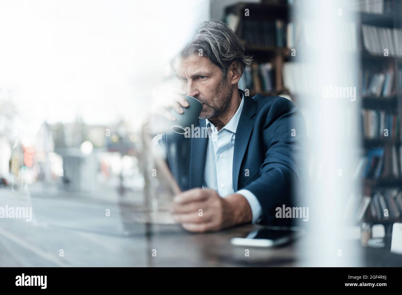 Geschäftsmann trinkt eine Kaffeetasse, während er die Zeitung im Café liest Stockfoto