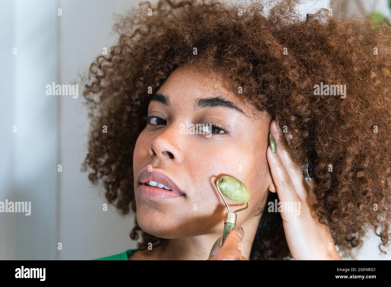 Junge Frau mit der Hand im Haar mit Jaderolle im Gesicht Stockfoto