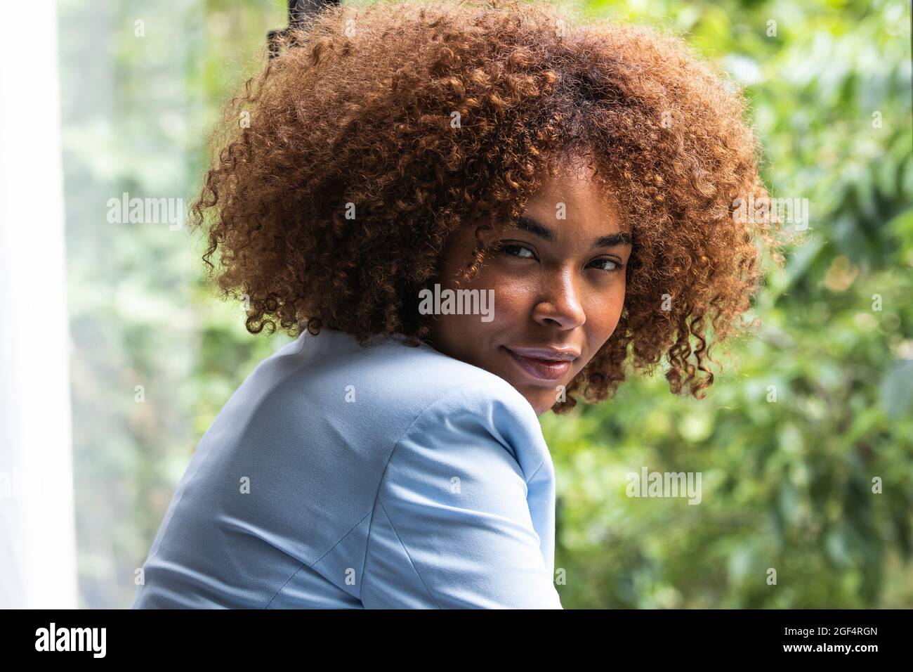 Junge professionelle Frau mit braunem lockigen Haar in blauem Blazer Stockfoto