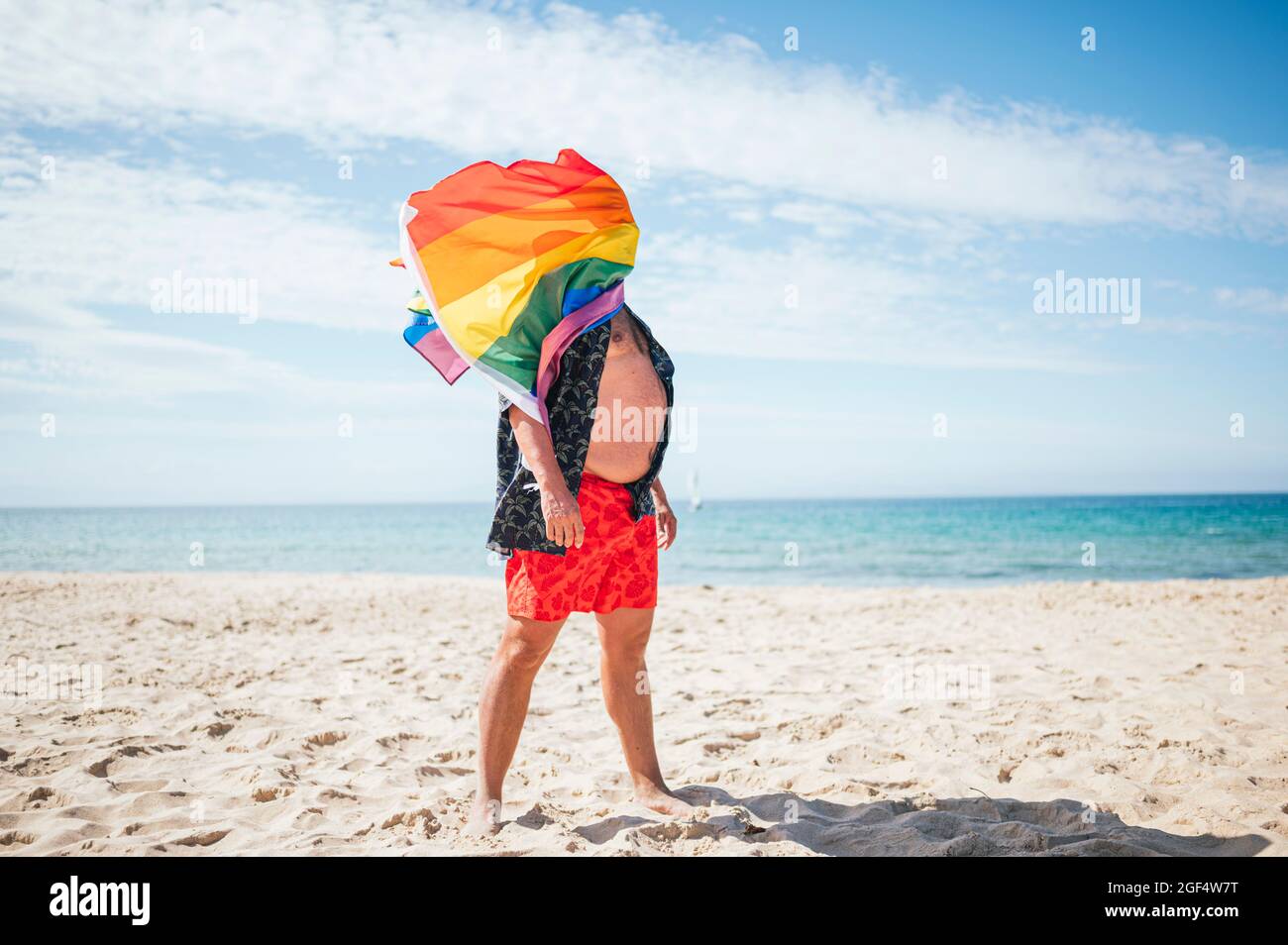 Schwuler Mann winkt Regenbogenfahne an sonnigen Tag Stockfoto